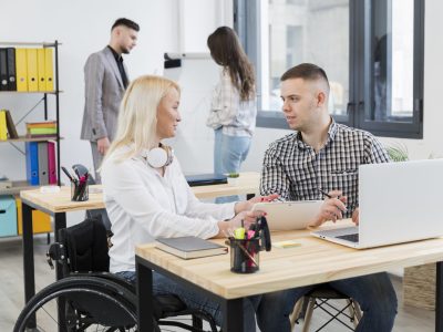 side-view-woman-wheelchair-discussing-with-coworker-her-desk